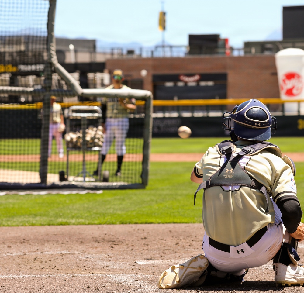 Baseball catcher in full gear receives pitch during batting practice at collegiate stadium