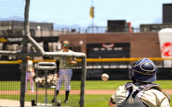 Baseball catcher in full gear receives pitch during batting practice at collegiate stadium