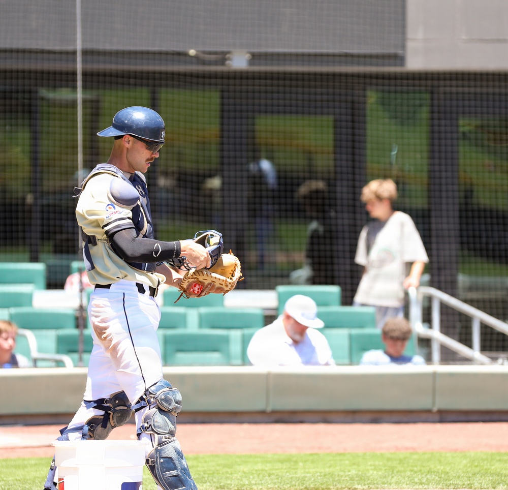 Baseball catcher in full gear stands near dugout during game at modern stadium