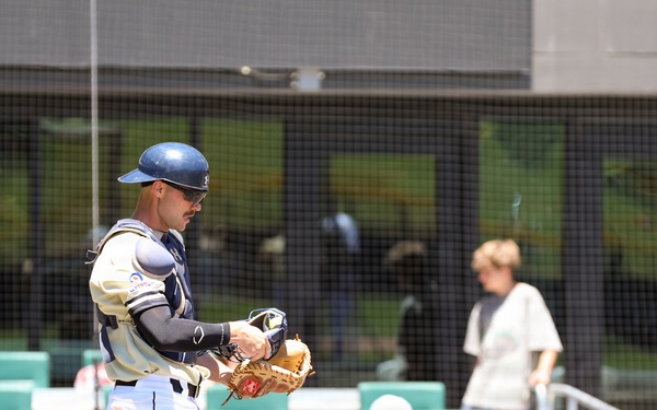 Baseball catcher in full gear stands near dugout during game at modern stadium