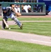 Baseball catcher scrambles to field a wild pitch near the first base line during a collegiate game