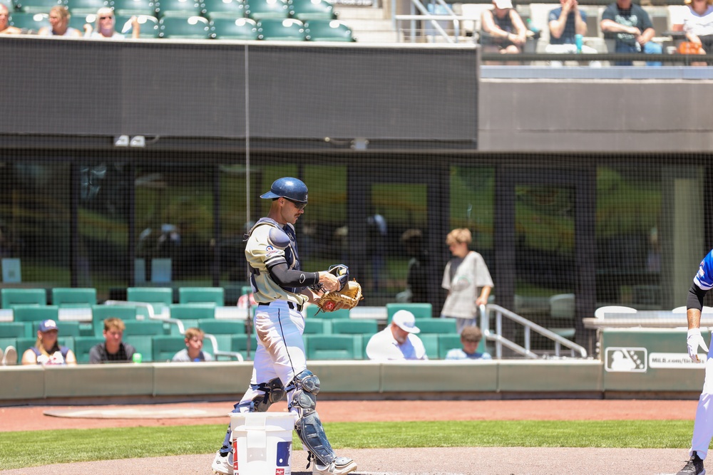 Baseball catcher walks near home plate during minor league game