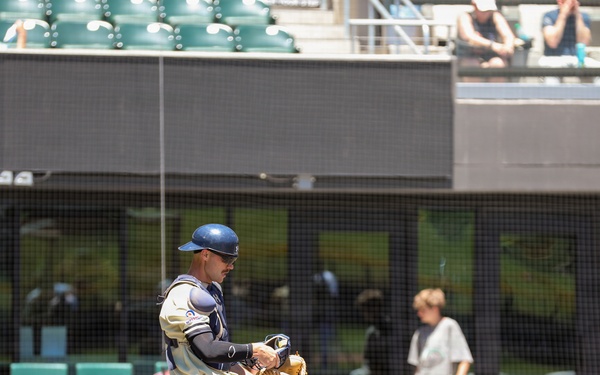 Baseball catcher walks near home plate during minor league game