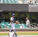 Baseball catcher walks near home plate during minor league game