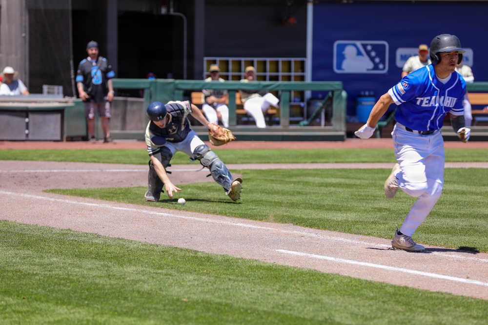 Team HHI batter races to first base as catcher lunges for dropped ball during MLB-affiliated military baseball game
