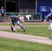Team HHI batter races to first base as catcher lunges for dropped ball during MLB-affiliated military baseball game