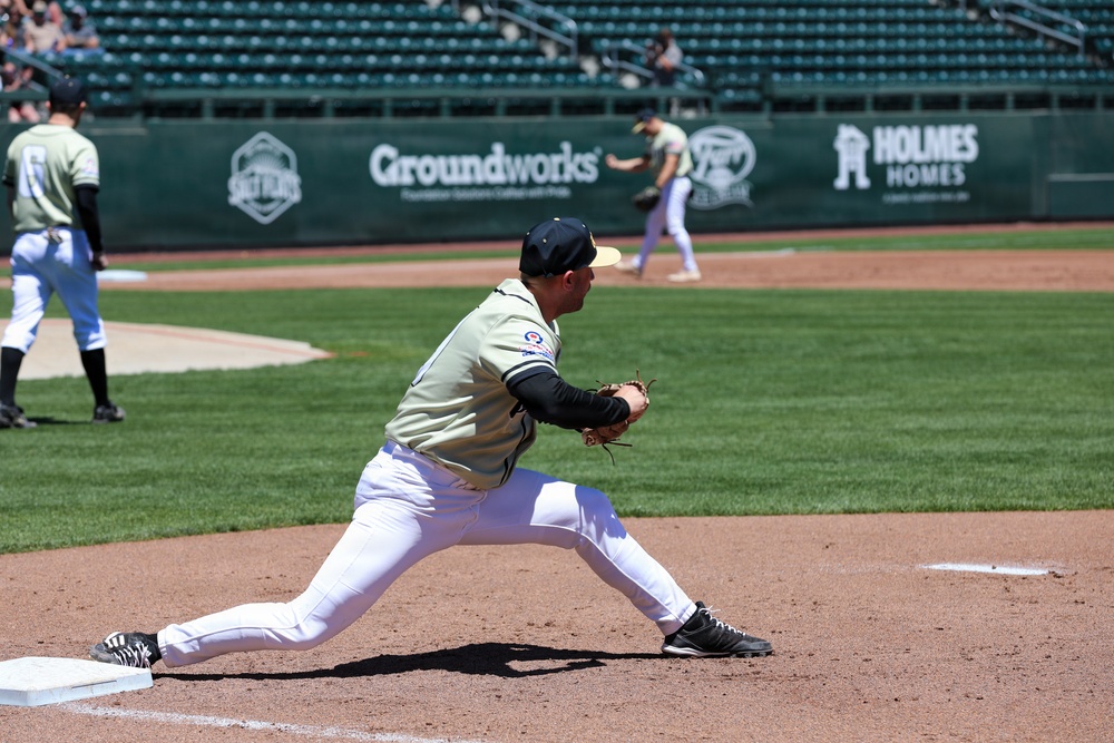Baseball player stretches to field a throw at first base during a minor league game
