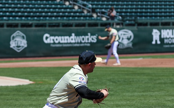Baseball player stretches to field a throw at first base during a minor league game