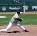 Baseball player stretches to field a throw at first base during a minor league game