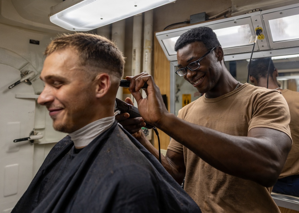USS Ross Sailor cuts hair in the barbershop