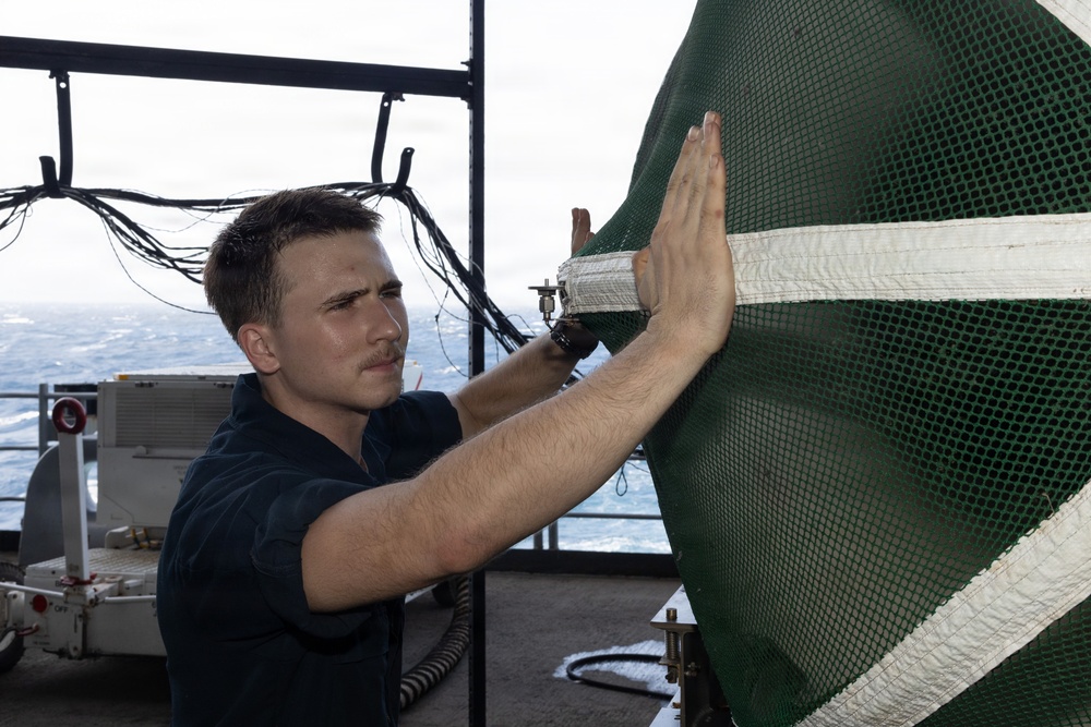USS George H.W. Bush Sailor places a protective mesh over the intake