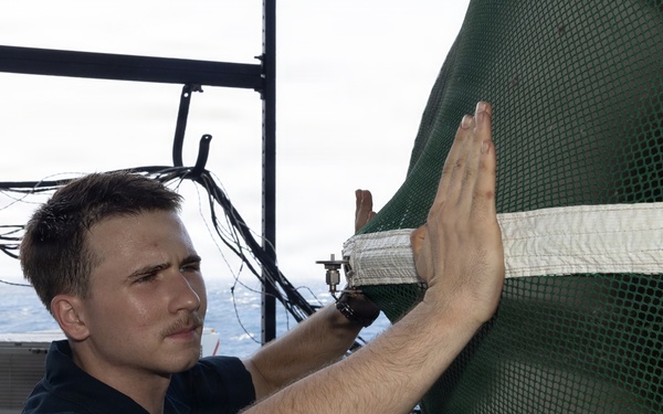 USS George H.W. Bush Sailor places a protective mesh over the intake