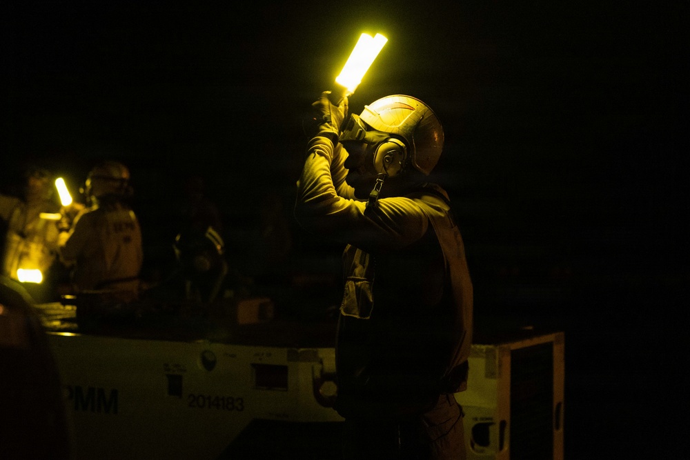 USS George H.W. Bush signals an aircraft tow tractor