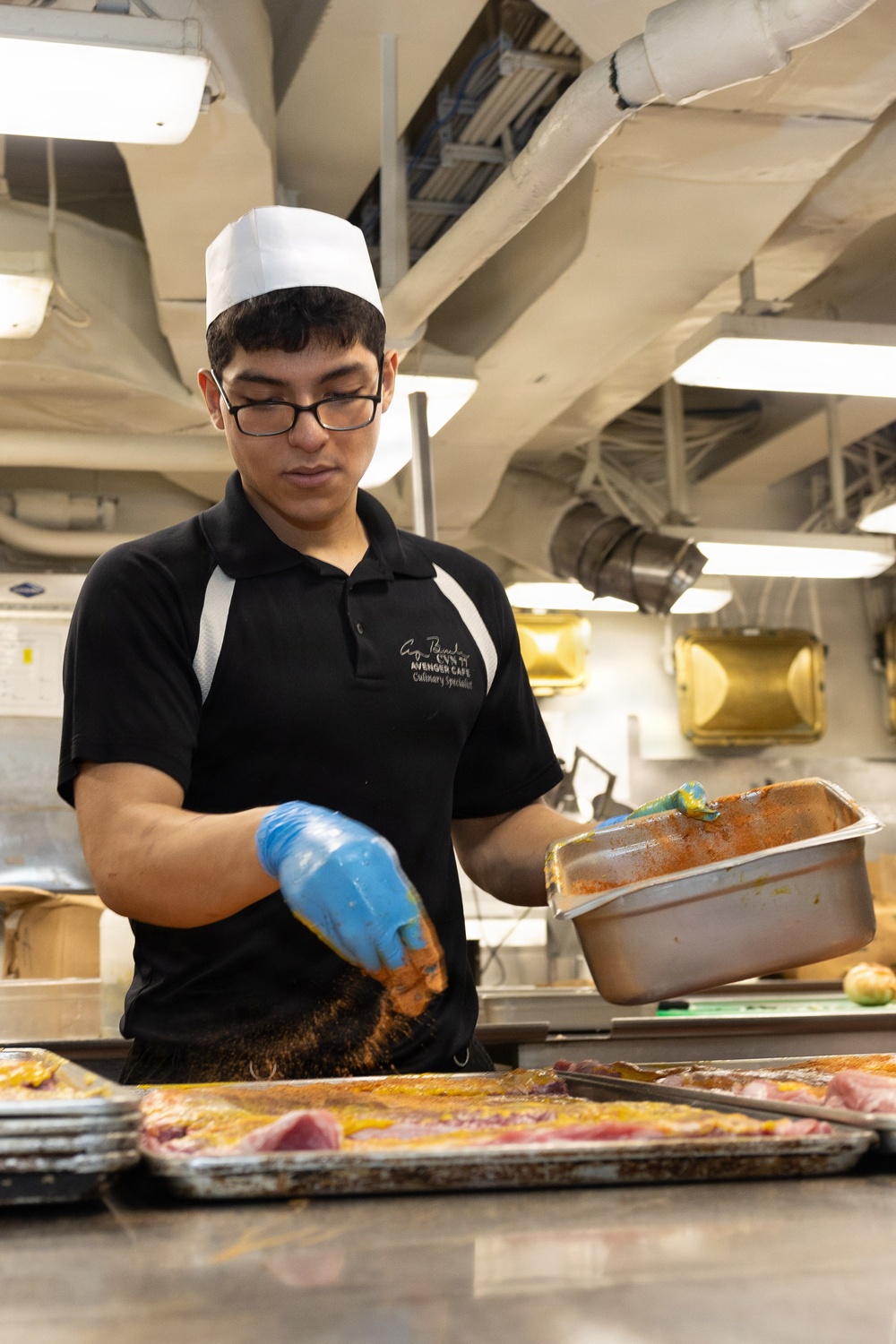 USS George H.W. Bush Sailor seasons chicken