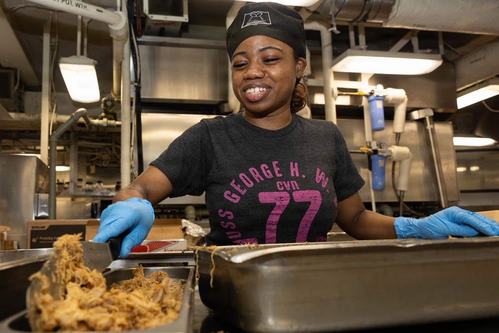 USS George H.W. Bush Sailor transfers food to a serving tray