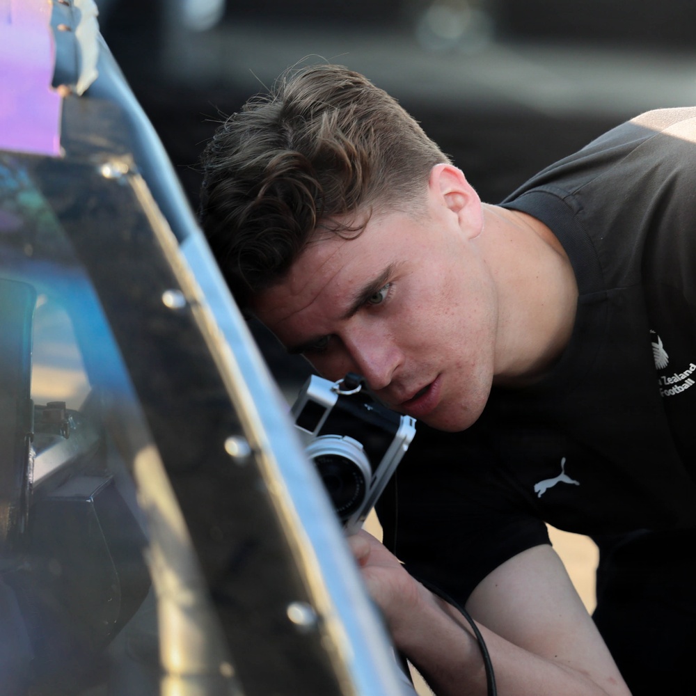 New Zealand National Football Team player takes photo of NASCAR race car
