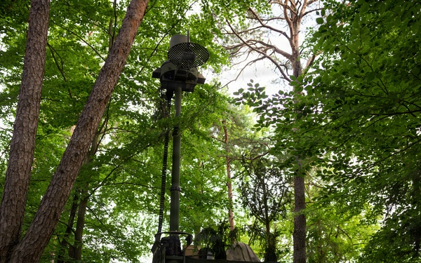 Soldiers operate military communications vehicle concealed in forest during Spectrum Blitz 26