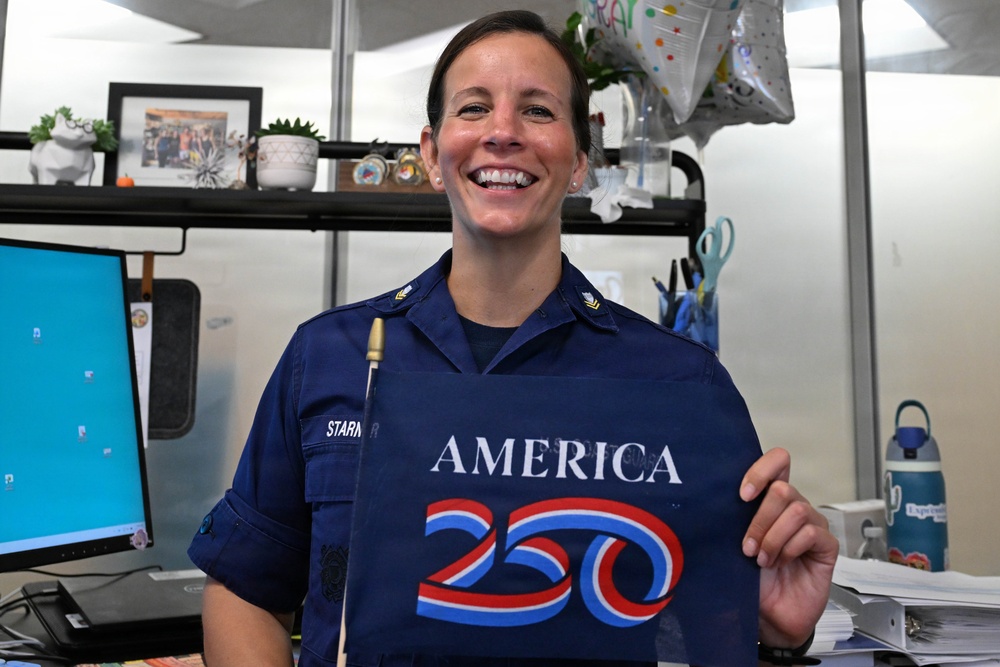 U.S Coast Guard Petty Officer 2nd Class Starner holds America 250 commemorative flag