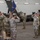 Task Force Vipers transfer authority to Task Force Gunfighters A military ceremony is taking place inside an aircraft hangar, with soldiers in OCP (Operational Camouflage Pattern) uniforms rendering salutes. A guidon bearer stands at center holding a blue and gold unit flag, while two groups of personnel face each other in a formal formation. The setting and posture suggest a change of command or activation/deactivation ceremony.