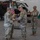 Task Force Vipers transfer authority to Task Force Gunfighters A military ceremony is taking place inside an aircraft hangar, likely a change of command or casing/uncasing of colors ceremony. Several U.S. Army soldiers in OCP (Operational Camouflage Pattern) uniforms are handling a blue and gold guidon or unit colors. A military helicopter, likely an AH-64 Apache, is visible in the background.
