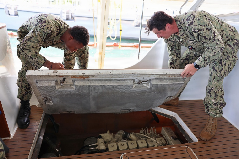 U.S. Navy Machinist’s Mate 2nd Class Zackery Herrel and Boatswain’s Mate 2nd Class Brandon Hollinger secure the engine hatches on the historic admiral's barge following routine maintenance at Joint Base Pearl Harbor-Hickam.