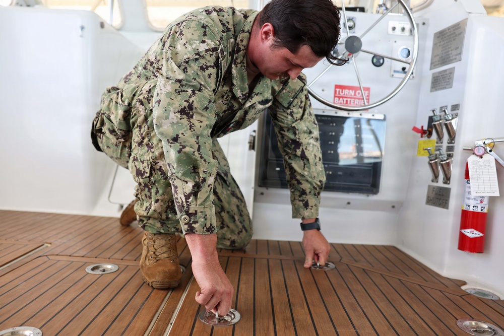 U.S. Navy Machinist’s Mate 2nd Class Zackery Herrel secures the engine hatches on the historic admiral's barge during routine maintenance at Joint Base Pearl Harbor-Hickam.