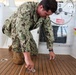 U.S. Navy Machinist’s Mate 2nd Class Zackery Herrel secures the engine hatches on the historic admiral's barge during routine maintenance at Joint Base Pearl Harbor-Hickam.