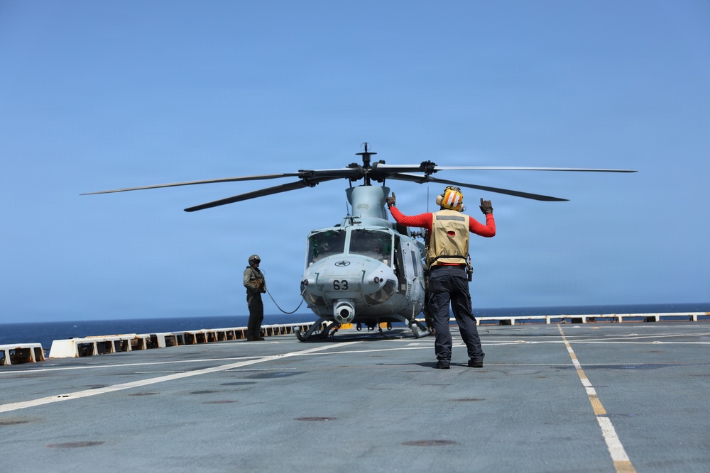 A U.S. Sailor signals a UH-1Y Venom helicopter, assigned to Marine Medium Tiltrotor Squadron (VMM) 365 (Reinforced), Littoral Combat Force 24.
