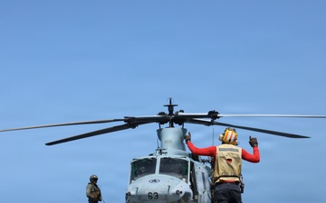 A U.S. Sailor signals a UH-1Y Venom helicopter, assigned to Marine Medium Tiltrotor Squadron (VMM) 365 (Reinforced), Littoral Combat Force 24.