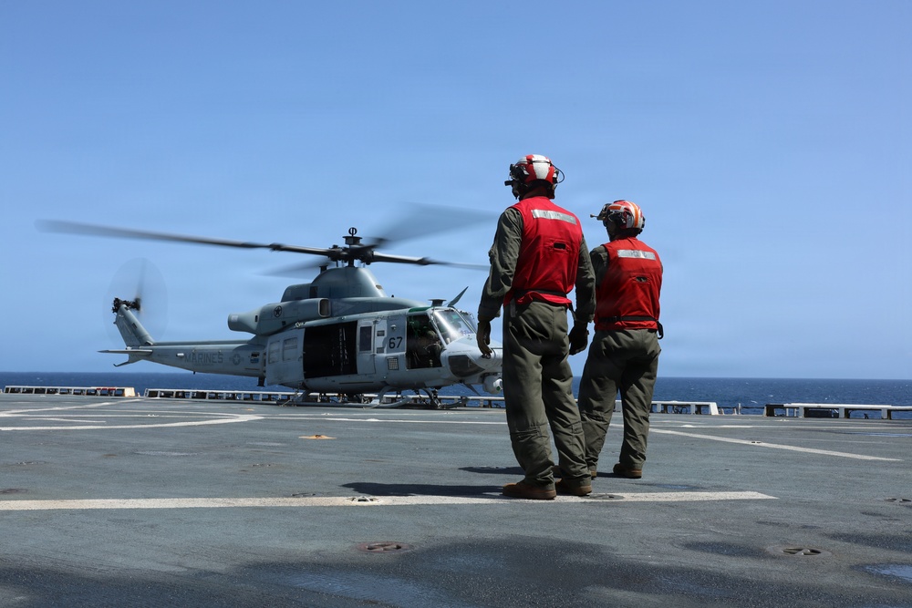 U.S. Marines signal a UH-1Y Venom helicopter, assigned to Marine Medium Tiltrotor Squadron (VMM) 365 (Reinforced), Littoral Combat Force 24.