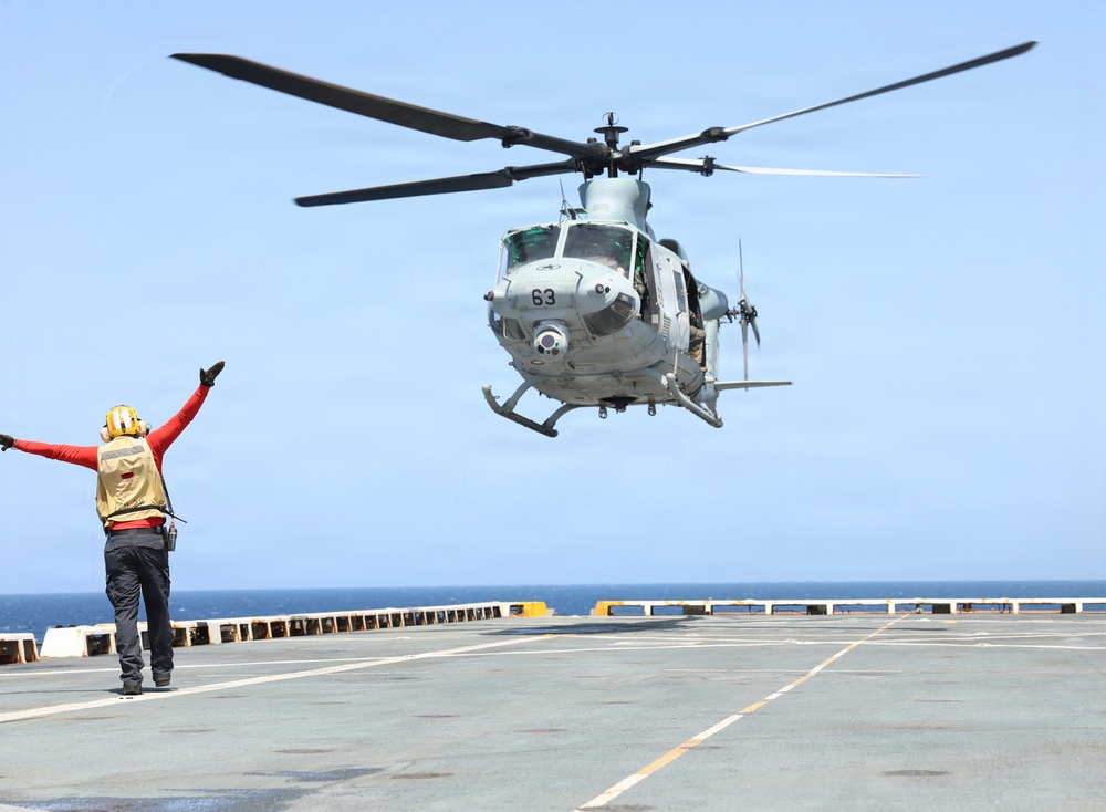 A U.S. Sailor signals a UH-1Y Venom helicopter, assigned to Marine Medium Tiltrotor Squadron (VMM) 365 (Reinforced), Littoral Combat Force 24.