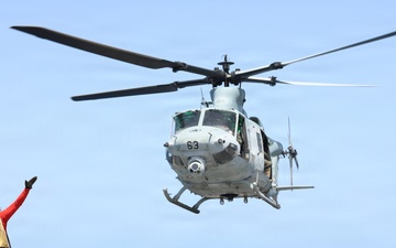A U.S. Sailor signals a UH-1Y Venom helicopter, assigned to Marine Medium Tiltrotor Squadron (VMM) 365 (Reinforced), Littoral Combat Force 24.