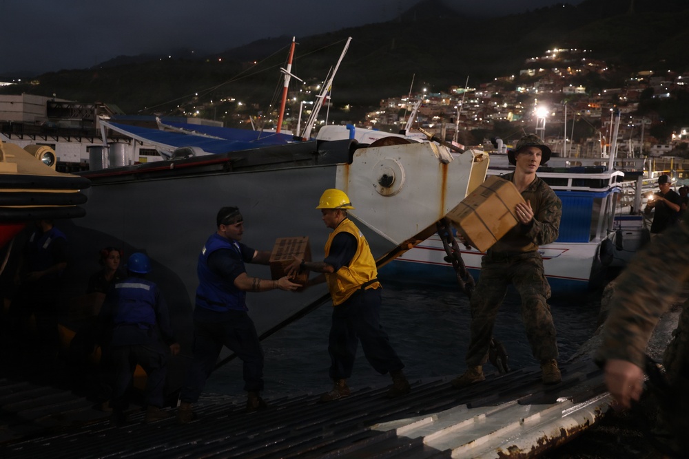 U.S. Sailors and Marines, with Littoral Combat Force 24, unload Meals, Ready-to-Eat boxes from Landing Craft Utility (LCU) 1662, assigned to Assault Craft Unit (ACU) 2, in La Guaira, Venezuela, June 27, 2026.