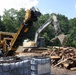 An excavator prepares to load hurricane debris into a carbonizer