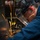 Hull Technicians Aboard USS Boxer Perform Welding, Grinding A worker is performing metal grinding or cutting on a flat metal sheet, producing a shower of bright orange and yellow sparks. The individual is wearing appropriate personal protective equipment including a face shield, hearing protection, and a blue work jacket. The image is captured in close-up, emphasizing the intensity of the sparks and the worker's focused posture.