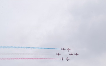 Royal Air Force Red Arrows perform over waterway as U.S. Coast Guard vessel patrols below