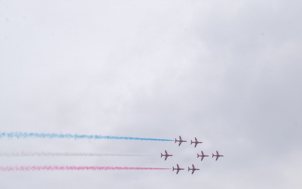 Royal Air Force Red Arrows perform over waterway as U.S. Coast Guard vessel patrols below
