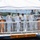 USS South Dakota (SSN 790) Holds Change of Command Ceremony A formal U.S. Navy ceremony is taking place on a platform labeled 'USS South Dakota,' with several naval officers in dress white uniforms gathered under a white canopy tent. The event appears to be a commissioning, change of command, or award ceremony conducted at a waterfront naval facility. Two officers stand at wooden podiums while others are engaged in what appears to be a pinning or award presentation in the center.