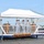 USS South Dakota (SSN 790) Holds Change of Command Ceremony A formal U.S. Navy commissioning or change-of-command ceremony is taking place aboard the USS South Dakota submarine. Several naval officers in white dress uniforms are on a decorated platform, with some rendering salutes. The event appears to be conducted at a naval base with waterfront facilities visible in the background.