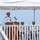 USS South Dakota (SSN 790) Holds Change of Command Ceremony A U.S. Navy officer in dress white uniform is delivering a speech at a podium during what appears to be a formal military ceremony. Three other naval officers in dress whites are seated in the background under a white canopy tent. The setting appears to be an outdoor waterfront location.