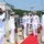 USS South Dakota (SSN 790) Holds Change of Command Ceremony A formal U.S. Navy ceremony is taking place on a pier or dock, featuring personnel in white dress uniforms rendering salutes along a red carpet. The scene appears to be a change of command, commissioning, or official arrival/departure ceremony. Multiple officers and enlisted sailors are positioned in a ceremonial formation near the waterfront.