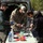 Deep Strike 10th Special Forces Group Three individuals are gathered around a folding table set up at the rear of an open van in an outdoor gravel area. One person is wearing a U.S. Army camouflage uniform, while the other two are in civilian clothing. They appear to be assembling or inspecting drone equipment.