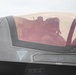 A close-up photograph of a military fighter jet cockpit, identified as belonging to Capt. J.J. 'STORQ' Metzger. A pilot wearing a flight helmet and oxygen mask is seated inside the cockpit beneath a tinted canopy. The aircraft displays standard safety markings including ejection seat warnings and rescue instructions.