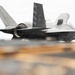 A U.S. Marines F-35B stealth fighter jet is captured in a low-angle shot, appearing to be on or just above a ship's deck, likely an amphibious assault ship. The aircraft displays 'MARINES' markings on the fuselage and tail code 'CF' with chevron stripes. The lift fan opening is visible on top of the fuselage, consistent with the F-35B short takeoff/vertical landing (STOVL) variant.