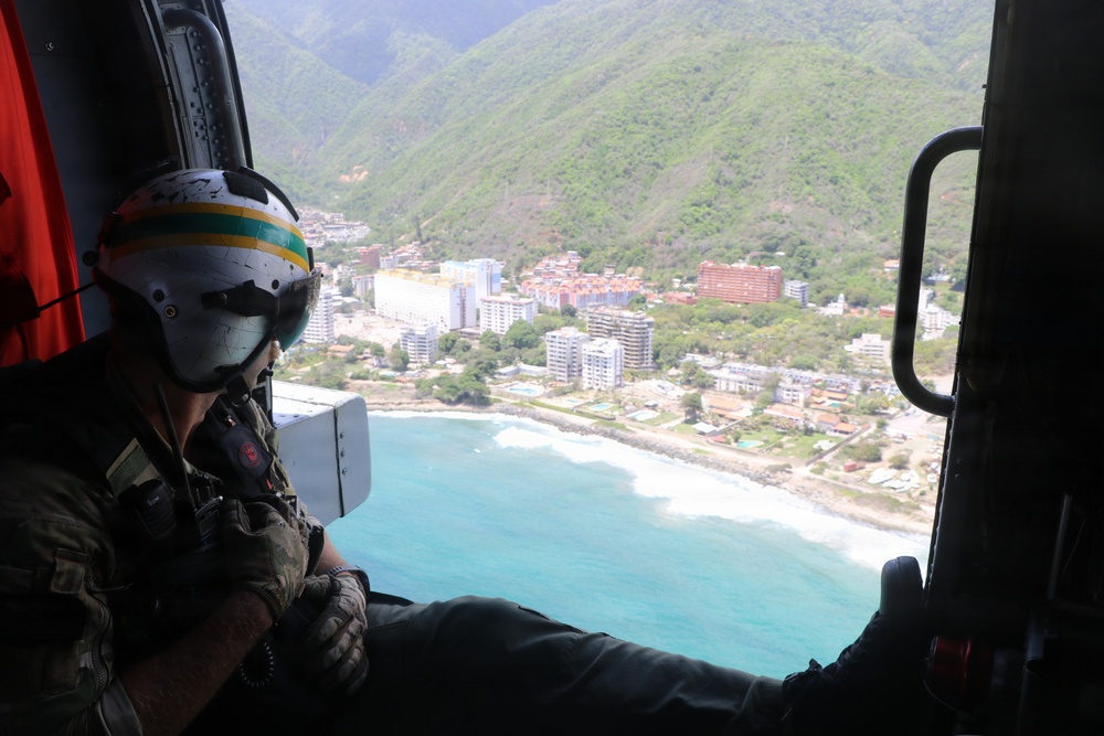 A U.S. Naval Aircrewman (Helicopter) scans the horizon from an MH-60R Seahawk, assigned to Helicopter Maritime Strike Squadron (HSM) 48 during flight operations off the coast of Venezuela, June 29, 2026.