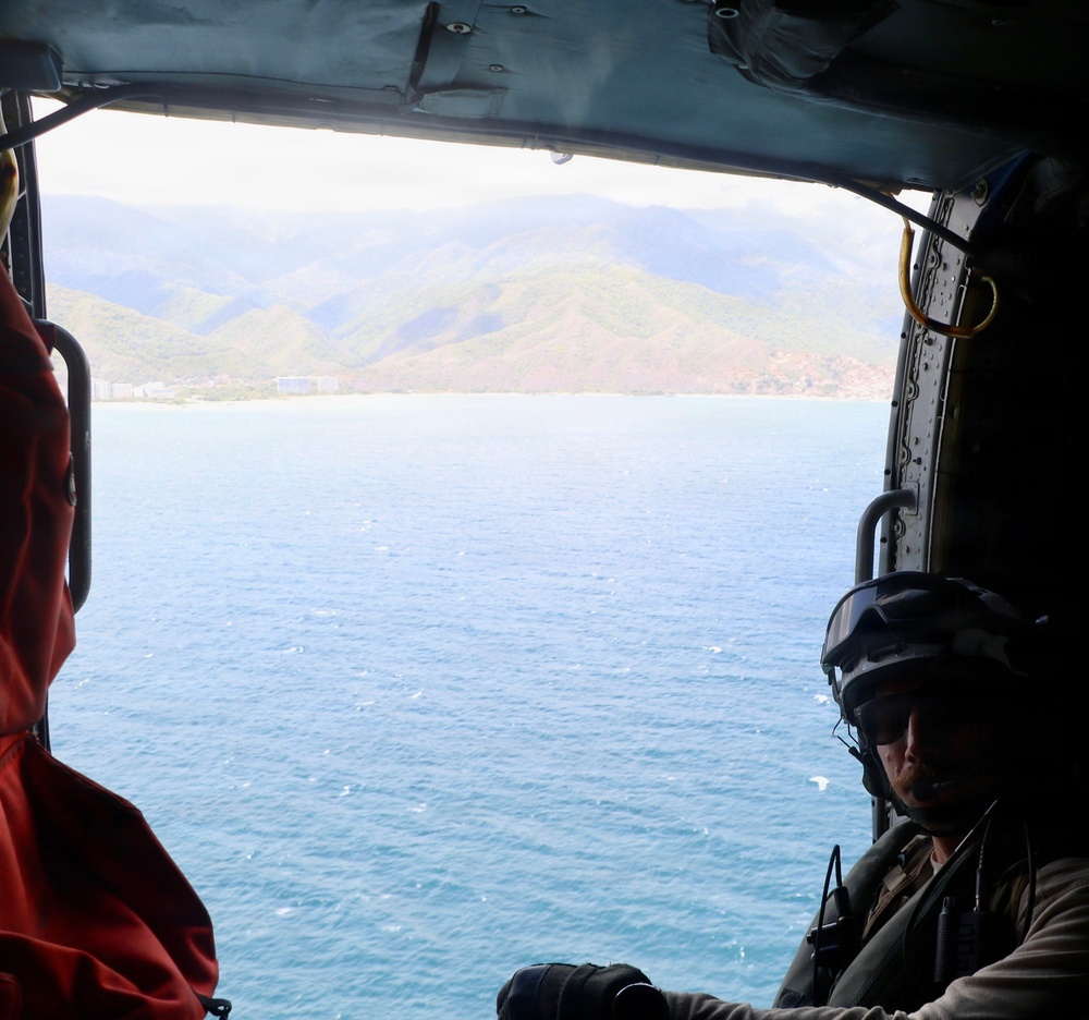A U.S. Naval Aircrewman (Helicopter) scans the horizon from an MH-60R Seahawk, assigned to Helicopter Maritime Strike Squadron (HSM) 48.