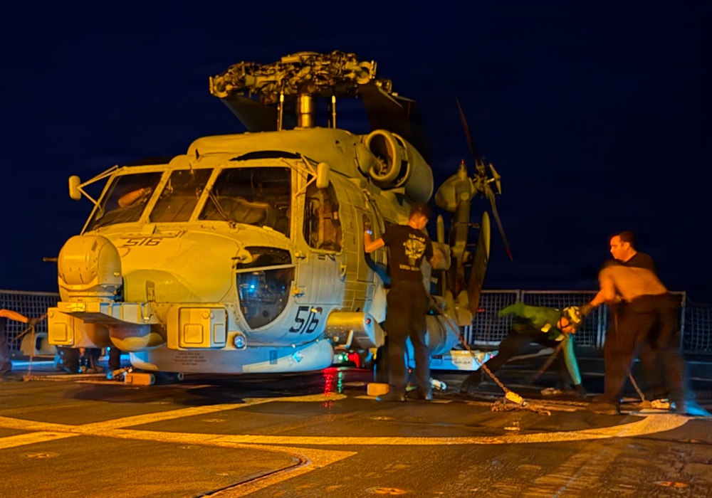Sailors secure an MH-60R Seahawk helicopter, assigned to Helicopter Maritime Strike Squadron (HSM) 48, to the flight deck.