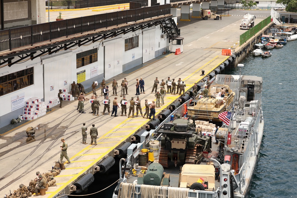 U.S. Marines, with 3rd Battalion, 2nd Marine Regiment, Littoral Combat Force-24, and U.S. Sailors, with San Antonio-class amphibious transport dock USS Fort Lauderdale (LPD 28), load supplies.
