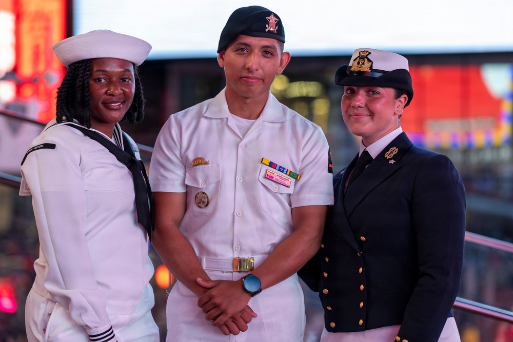 U.S. Navy Sailors pose with a British Royal Navy Sailor for a photo in Times Square in New York