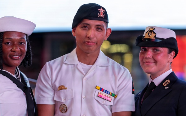 U.S. Navy Sailors pose with a British Royal Navy Sailor for a photo in Times Square in New York